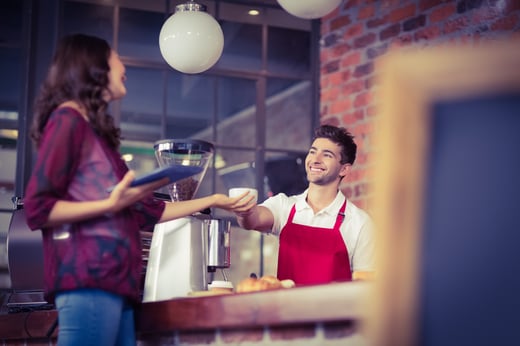 Smiling waiter serving a client at the coffee shop